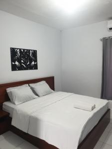 PawenangBTN Mahkota Pemenang 13 Tamarin 3A的卧室内的一张带白色床单和枕头的床