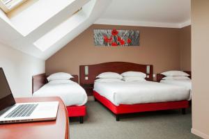 阿拉斯Brit Hotel Arras的一间卧室配有三张床,书桌上配有一台笔记本电脑
