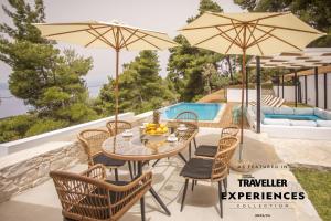 斯基亚索斯镇Allure Luxury Villas的天井配有桌椅和遮阳伞。