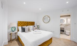 伦敦Flat 205的一间卧室配有一张带白色床单和镜子的大床