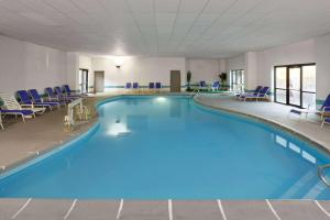 印第安纳波利斯印第安纳波利斯西北戴斯酒店的一座大型游泳池,位于酒店带蓝色椅子的房间内