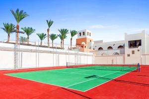 加利布港Pickalbatros Sands Port Ghalib的一座棕榈树建筑前的网球场