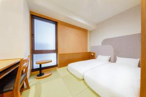 京都Hop Inn Kyoto Shijo Omiya的一间卧室设有两张床、一张桌子和一个窗口。