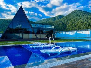 盖贝莱Qafqaz Royal Chalet的一个带椅子的游泳池和一个背景为山脉的建筑