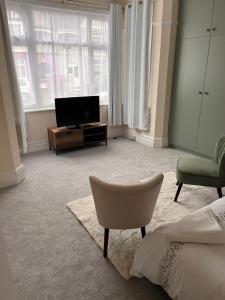 伦敦Luxury Cosy Retreat Apt的酒店客房配有一张床、一台电视和一把椅子