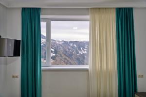 KhuloHotel Lile • სასტუმრო ლილე的山景窗户,配有绿色窗帘
