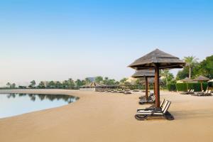 多哈多哈君悦别墅酒店的海滩上设有躺椅和遮阳伞,