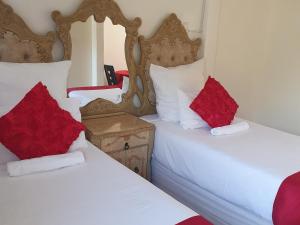 恩潘盖尼Mesda Bed & Breakfast的客房内的两张床和红色枕头