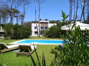 何塞伊格纳西奥Mar, Bosque y Lago的一个带2把躺椅的游泳池以及1栋房屋