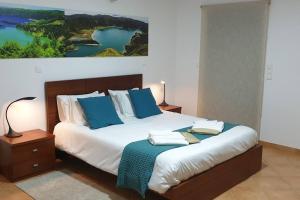 蓬塔德尔加达A Caminho da Ilha的一间卧室配有一张带蓝色枕头的大床