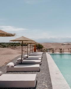 El KariaEmeraude Camp Agafay的游泳池旁一排带遮阳伞的躺椅