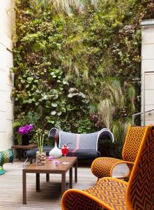 马赛C2酒店的庭院配有桌椅,墙上挂有植物