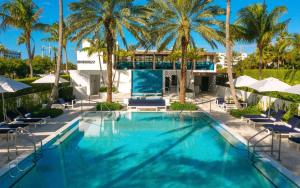 棕榈滩Tideline Palm Beach Ocean Resort and Spa的一座棕榈树和椅子的游泳池以及一座建筑
