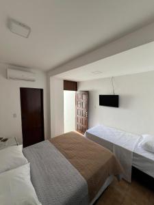 若昂佩索阿Pousada Mangai的一间卧室配有两张床和一台平面电视