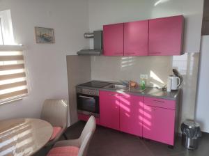 珀德垂那Apartments Blaža的粉红色的厨房设有水槽和炉灶