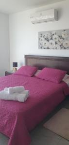 萨利纳斯Jade Aparts Salinas的紫色的床,上面有两条白色毛巾