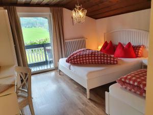 滕嫩山麓圣马丁Boutique Hotel Alpenhof的一间卧室配有两张带红色枕头的床和窗户。