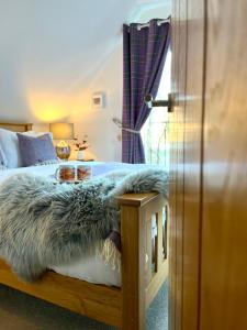 巴拉胡利什Bluebell Cottage with Hot Tub的一间卧室配有一张床,床上有毛皮毯子