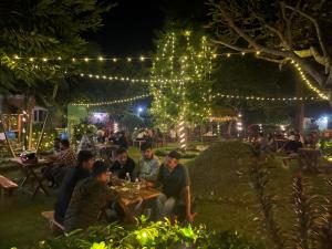 奇旺Hotel Tharu Garden And Beer Bar的一群人晚上坐在花园里的桌子上