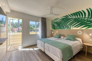 马斯帕洛马斯科迪尔绿色高尔夫简易别墅的卧室配有一张墙壁上绿叶茂密的床。