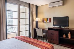 圣保罗DELPLAZA Marabá São Paulo的酒店客房配有一张床和一张书桌及一台电视