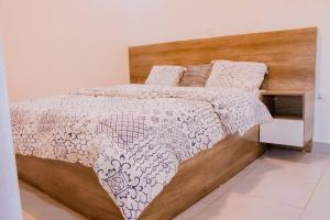 基加利The Vacation Homes Apartments的一间卧室配有一张带木制床头板的床
