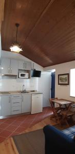 阿加尼尔Casa do Loureiro的厨房配有白色橱柜和木制天花板