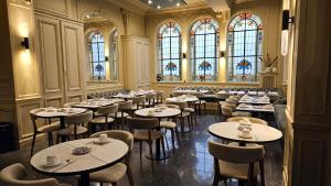 巴黎贝尔维尤和黄金战车酒店的用餐室配有桌椅和彩色玻璃窗