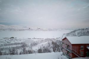 里克斯格伦森Ski in ski out lägenhet med fantastisk utsikt的雪地中的红色建筑,享有田野的景色