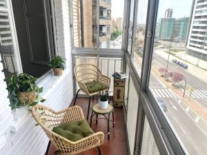 萨拉戈萨Acogedor apartamento a 5 min del Ave的阳台配有两把椅子和一张桌子,窗户