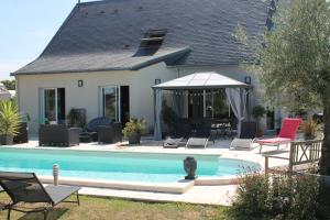Saint-Gervais en-Belin农场住宿加早餐旅馆的一座房子,设有游泳池、椅子和遮阳伞