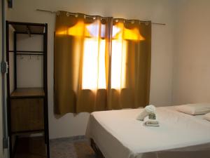 卡拉瓜塔图巴Pousada Yurgs的一间卧室配有床和带窗帘的窗户