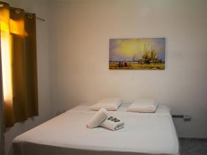 卡拉瓜塔图巴Pousada Yurgs的卧室配有两张白色床,墙上挂有绘画作品