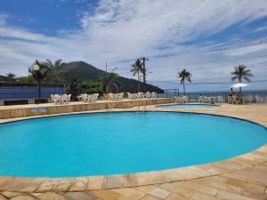 卡拉瓜塔图巴Maravilhoso apto à beira-mar的一个带椅子的大型蓝色游泳池,并享有海景
