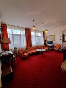 卡库拉塔Hotel Perla Oltului的客厅配有橙色椅子和红地毯