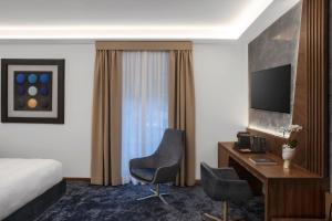 罗马Hotel Via Veneto的酒店客房配有一张床、一张书桌和一台电视。
