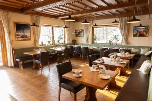 拉姆绍达赫斯坦Pension Dachsteinhof的餐厅设有木桌、椅子和窗户。