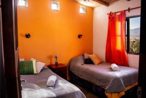 卡奇Cabaña Paraíso Cachi的橙色墙壁和窗户的客房内的两张床