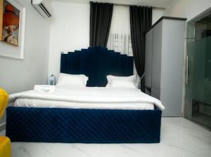 拉各斯The Duch Apartments的一间卧室配有一张大床和蓝色床头板