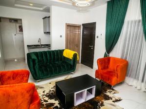 拉各斯The Duch Apartments的客厅配有绿色沙发和两把橙色椅子