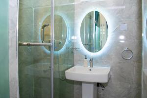 拉各斯The Duch Apartments的浴室配有盥洗盆和带镜子的淋浴
