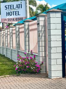 雅瓜里乌纳Hotel Stelati的围栏旁有粉红色花的旅馆标志