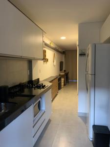 塔曼达雷FLAT ECO RESORT PRAIA DOS CARNEIROS的厨房配有白色橱柜和冰箱。