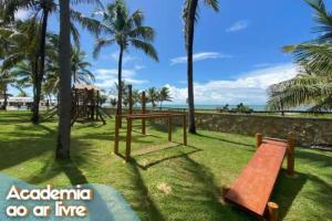 CamassariItacimirim Villas da Praia的一个带长凳和棕榈树的公园和海洋