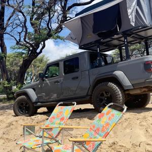 帕依亚Embark on a journey through Maui with Aloha Glamp's jeep and rooftop tent allows you to discover diverse campgrounds, unveiling the island's beauty from unique perspectives each day的两把椅子和一辆吉普车停在沙子里