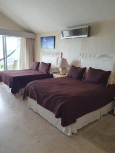 Banco PlayaPuerta del Mar Cozumel的一间卧室配有两张带紫色枕头的床