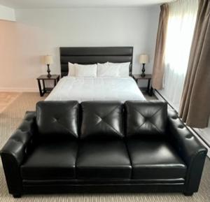 乔治王子城Anavada Inn & Suites - Prince George的卧室里一张黑色皮沙发,卧室里配有一张床