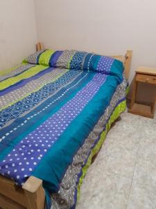 阿肖海Complejo Extremo的一张床上,床上有色彩缤纷的床单