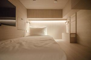 新加坡Jyu Capsule Hotel的一间卧室配有一张白色的床,光线充足