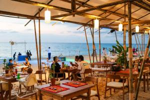 纳泰海滩Santhiya Phuket Natai Resort & Spa的一群坐在海滩桌子上的人
